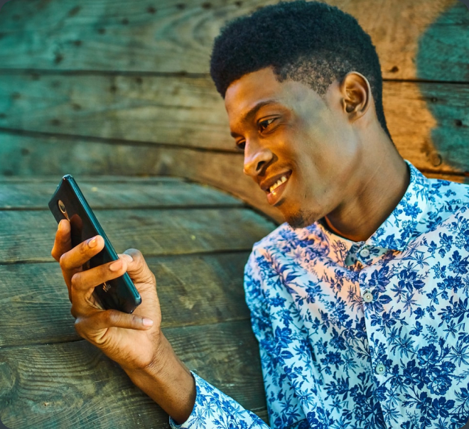 A happy man uses FarmVest application on his smartphone.